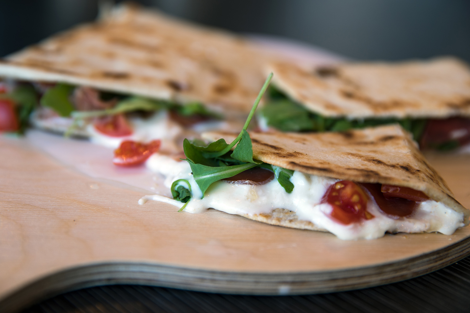 Detail Typical Italian freshly baked stuffed Italian piadina, similar to the spianata or tortillas stuffed with raw ham, rocket salad and melted stracchino cheese Turin Italy September 2018